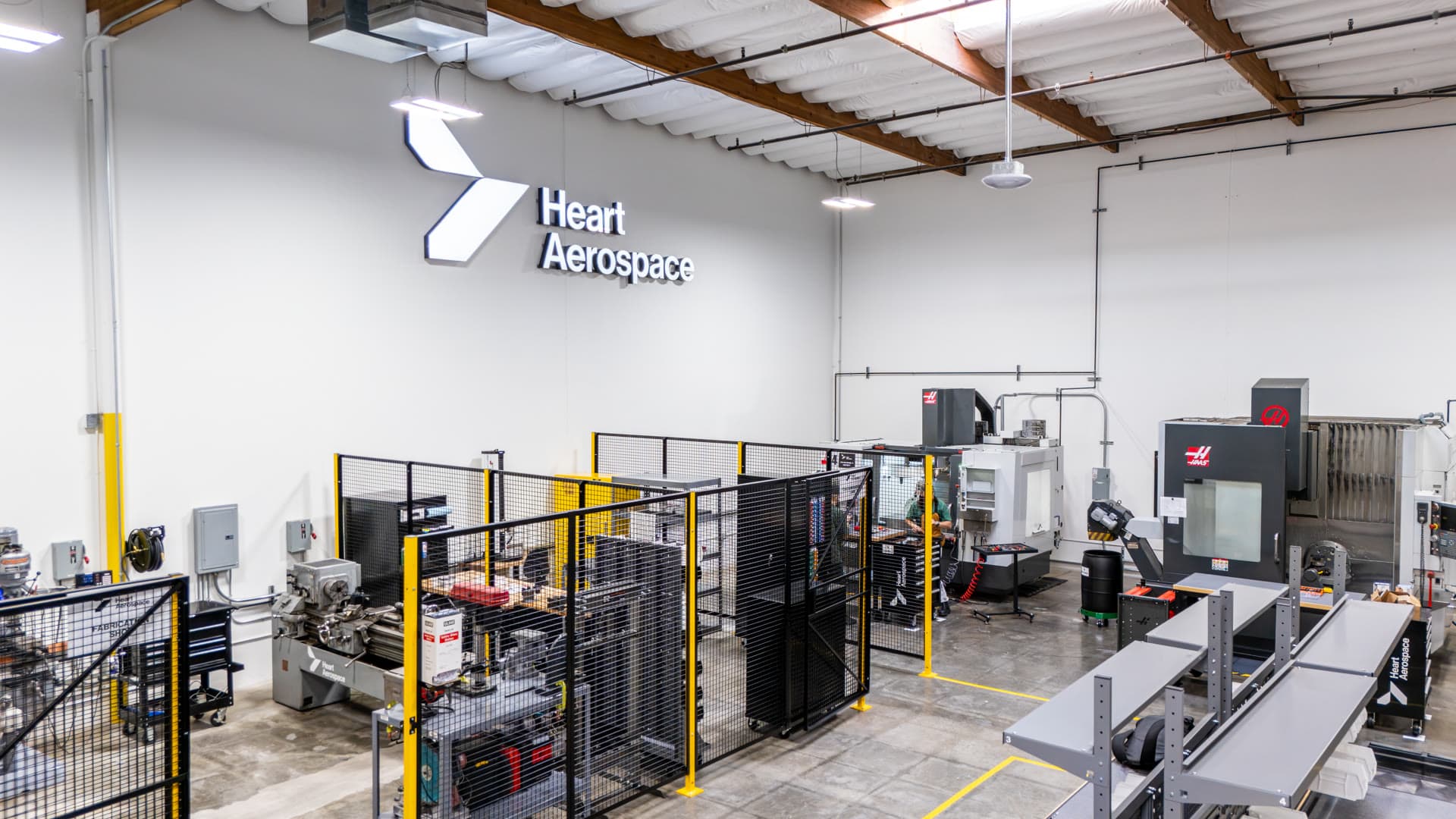 Machine shop at the Heart Aerospace Los Angeles R&D center, with CNC machining centers and the Heart Aerospace logo on the wall
