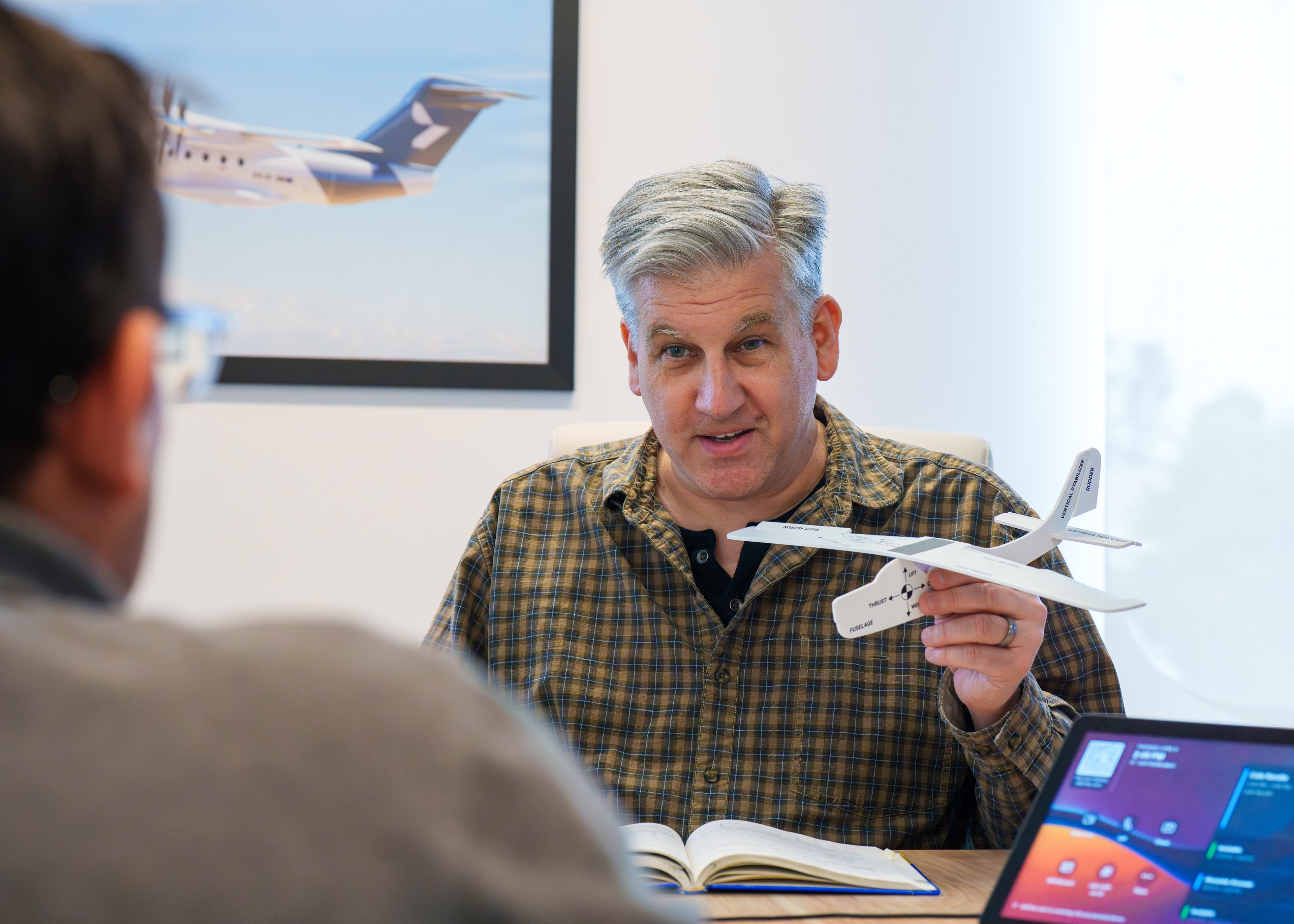 Two Heart Aerospace team members in discussion at a table, one holding a model of the ES-30 aircraft